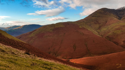 Scenic valley in autumn with snow capped mountain peaks. Touristic destination in the Lake District, Cumbria, United Kingdom. Top aerial view of peaks.