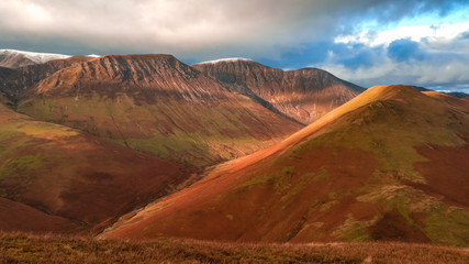 Scenic valley in autumn with snow capped mountain peaks. Touristic destination in the Lake District, Cumbria, United Kingdom. Top aerial view of peaks.
