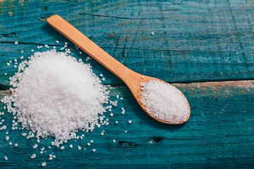 sea salt in wooden spoon on blue wooden board