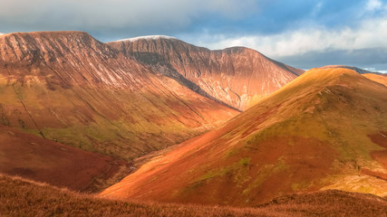 Naklejka premium Scenic valley in autumn with snow capped mountain peaks. Touristic destination in the Lake District, Cumbria, United Kingdom. Top aerial view of peaks.