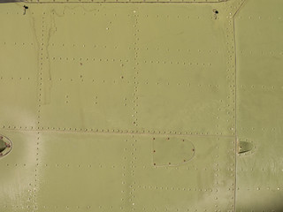 Old green metal surface of the aircraft fuselage with rivets