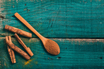 cinnamon in wooden spoon on blue wooden board