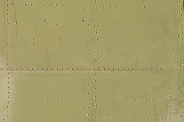 Old green metal surface of the aircraft fuselage with rivets