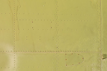 Old green metal surface of the aircraft fuselage with rivets