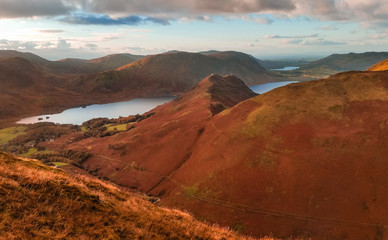 Scenic valley in autumn with snow capped mountain peaks. Touristic destination in the Lake District, Cumbria, United Kingdom. Top aerial view of peaks.