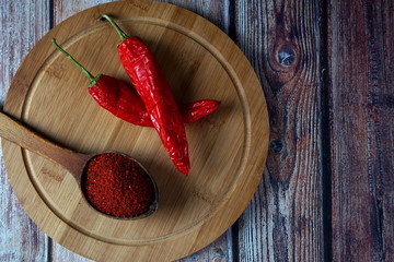 Ground red hot pepper in a wooden spoon on a cutting Board
