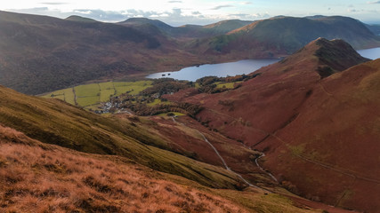 Scenic valley in autumn with snow capped mountain peaks. Touristic destination in the Lake District, Cumbria, United Kingdom. Top aerial view of peaks.