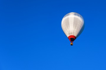 Balloon flight with a basket filled with people on a background of blue sky. 