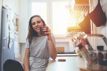 young woman drinking coffee in her kitchen