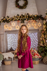 Fototapeta na wymiar A girl near the Christmas tree. Beautiful child decorates a Christmas tree. Portrait of a girl with long hair