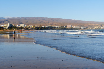 Gran Canaria - Wellen an der Küste von Playa Del Ingles mit den vulkanischen Bergen im Hintergrund