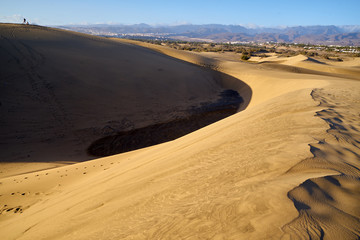 Sandberge von der Sahara - Dünenlandschaft am Strand von Gran Canaria mit den vulkanischen Bergen im Hintergrund