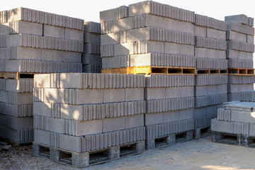 stacks of concrete blocks on pallets at a construction material wearhouse ready for sale. concrete blocks are widely used in building construction. isolated on white background.