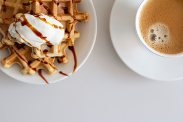 sweet waffles with yogurt syrup and banana on a white cup and black coffee