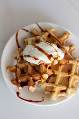 sweet waffles with yogurt syrup and banana on a white cup close-up