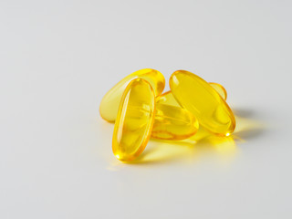 Omega 3 fish oil capsules isolated on white background. Golden color capsules - vitamin E, D or multivitamin.