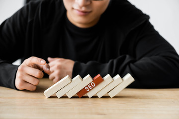cropped view of seo manager pointing with finger at wooden rectangles with lettering seo