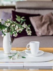Coffee table with a decorative bush branch with berries and sofa with pillows in the background
