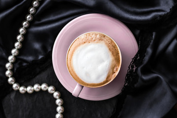 Cup of cappuccino for breakfast with satin and pearls jewellery background, organic coffee with...