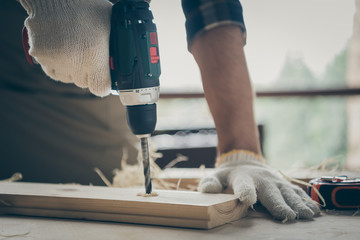 Cropped close-up view of his hands skilled experienced repairman specialist expert creating new gift shop project start-up home decor drilling hole using electrical device on table desk
