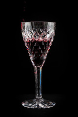 Red wine in a cut crystal wine glass isolated on a black background