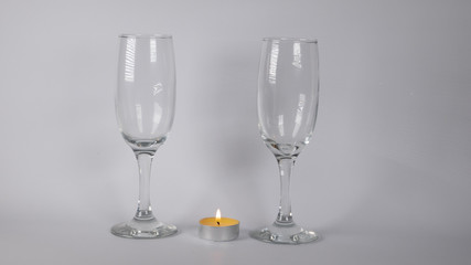 Burning candle near glasses of champagne, on a white background