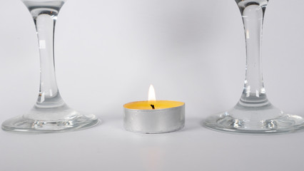 Burning candle near glasses of champagne, on a white background