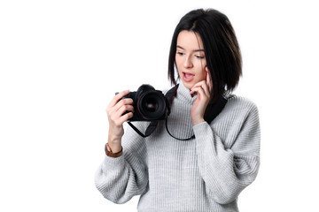 teenage girl in looking at the photo camera in her hands with curious and surprised expression on her face