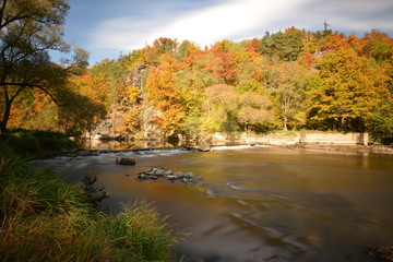river and old weir in forest in autumn long exposure