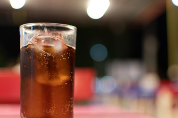 Soft drink glass placed on the table with the bokeh blur background.