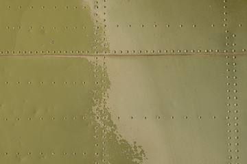 Old green metal surface of the aircraft fuselage with rivets