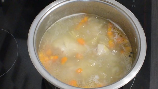 Chicken stock cooked in a pan on an induction stove