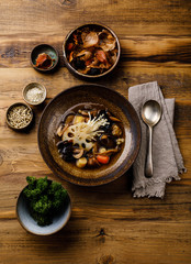 Healing Soup with roots, mushrooms and barley on wooden table background