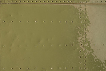 Old green metal surface of the aircraft fuselage with rivets