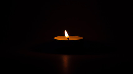 Burning candle on the table, dark background