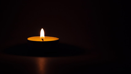 Burning candle on a meditation table, dark background