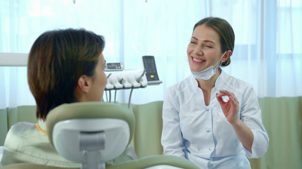 Dentist puts on a mask while talking with a woman