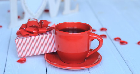 Cup of coffee and gift on blurred background.