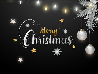 Calligraphy Merry Christmas text decorated with stars, hanging baubles, pine leaves and lighting garland on black background.