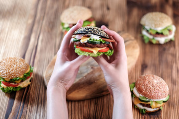 Woman in holding in her hands burger and 4 burgers on background with different fillings