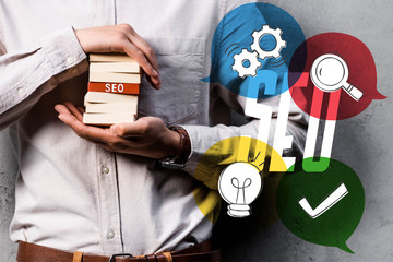 cropped view of seo manager holding wooden rectangles and standing near seo illustration