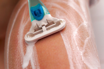 Girl shaves her legs with a razor, spreading foam on them
