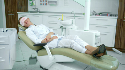 Fototapeta premium Tired doctor sleeps on a dental chair