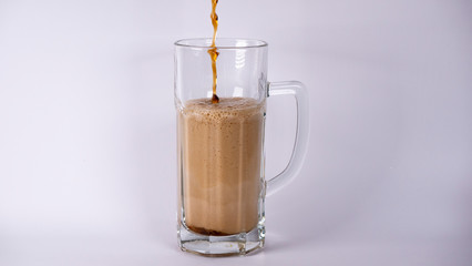 Pour beer into a glass with dark beer and foam on a white background