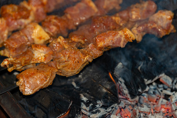 Roasted meat on skewers is cooked over burning coals.