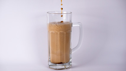 Pour beer into a glass with dark beer and foam on a white background
