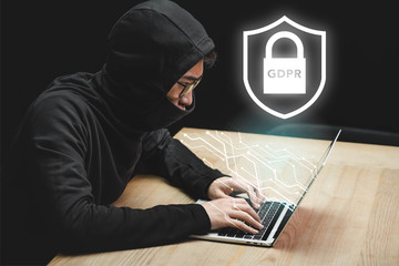 asian hacker using laptop and sitting near padlock illustration and gdpr lettering