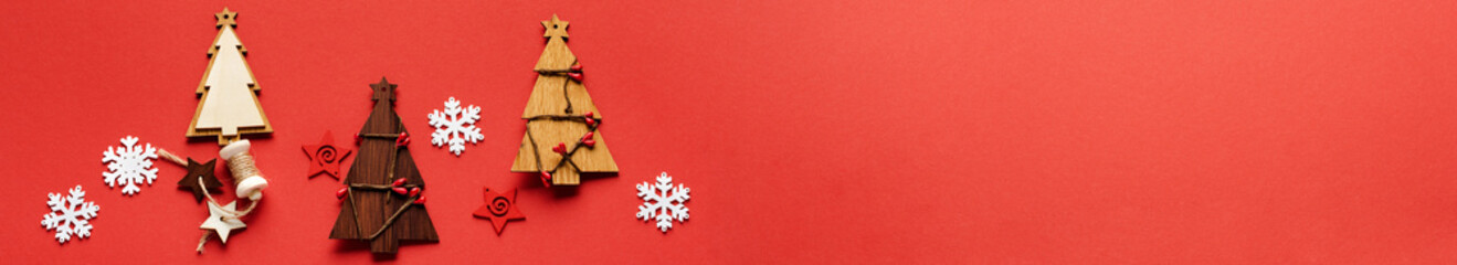 Fototapeta premium Christmas pattern made of Wooden Christmas fir tree toys, snowflakes and stars on red background. Flat lay, top view. New year concept. Top view, minimal christmas style and holiday concept. 