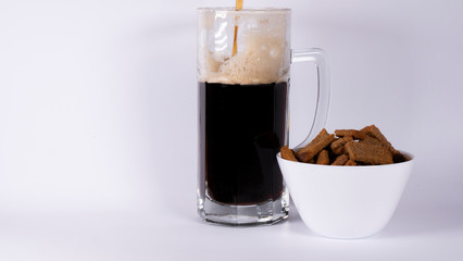 Beer glass with dark beer and crackers on a white background