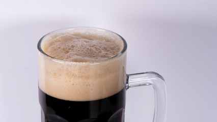 Beer glass with dark beer and foam on a white background